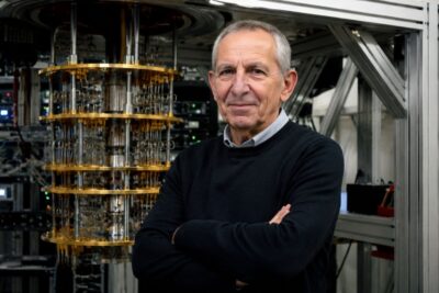 La Intel·ligència Artificial: Un Desafiament per a la Societat Michel Devoret, Premio Nobel de Física 2025 y científico de Google Quantum AI, posa junto a un ordenador cuántico.